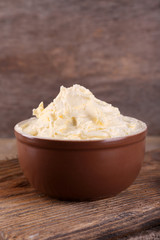 Fresh homemade butter in bowl, on wooden background