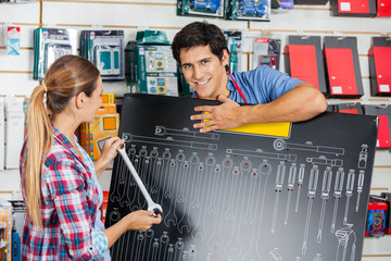 Salesman With Customer Examining Wrench Size Using Board