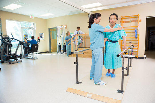 Therapists Assisting Patients In Hospital Gym