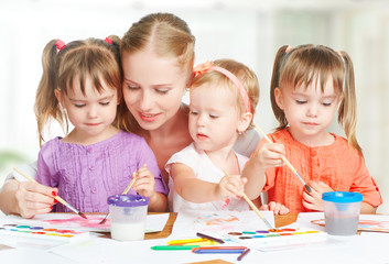 children twin sisters draw paints with mother