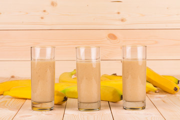 Banana smoothie and fruits on wood.