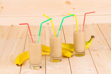 Banana smoothie and fruits on wood.