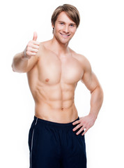 Man with muscular torso shows thumbs up sign.