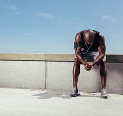 Tired young runner leaning over to catch his breath