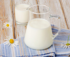Obraz na płótnie Canvas Jug and glass of milk on wooden background