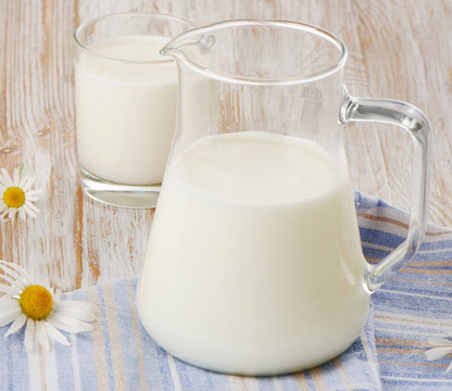 Jug and glass of milk on a wooden background