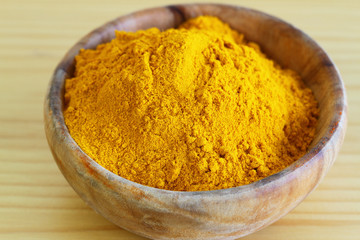 Tumeric powder in wooden bowl, close up