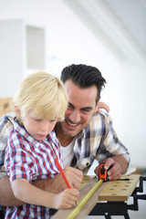 Father with kid measuring wood plank