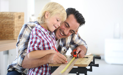 Father with kid measuring wood plank