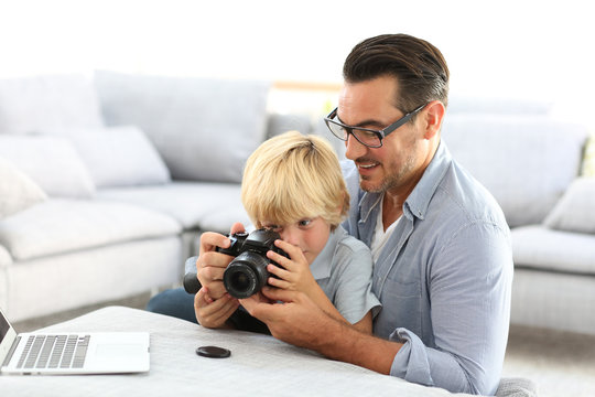 Man with little boy playing with reflex camera