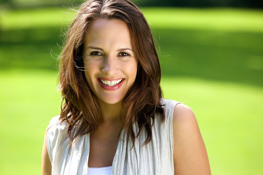 Smiling woman with brown hair posing outdoors