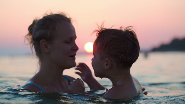 Mother and son having fun in sea at sunset