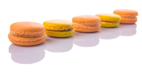 Yellow and orange colored French macarons on white background