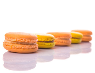 Yellow and orange colored French macarons on white background