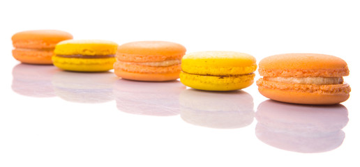 Yellow and orange colored French macarons on white background