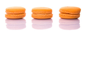 Orange colored French macarons over white background