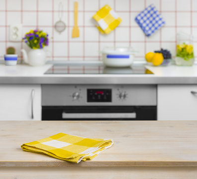 Wooden table with yellow napkin on kitchen background