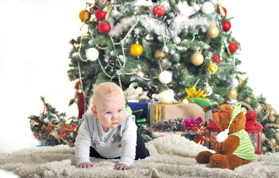 Cute baby one year boy playing with Christmas tree decoration