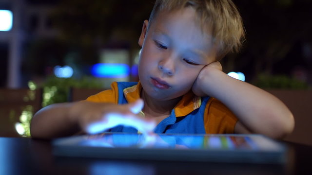 Bored little boy using pad in cafe