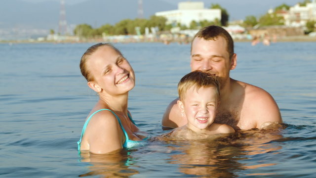 Happy parents and son bathing in sea on resort