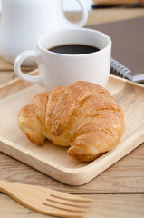 Black coffee with croissants on the wooden tray