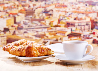 cup of coffee and croissants over cityscape