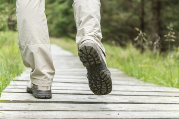 Hiking man with boots on wooden trail