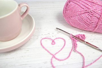 pink crochet background with yarn heart and coffee cup - obrazy, fototapety, plakaty
