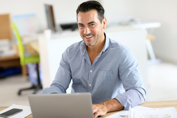 Obraz premium Businessman sitting in office and working on laptop