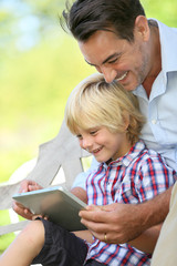 Daddy and son playing with tablet outside