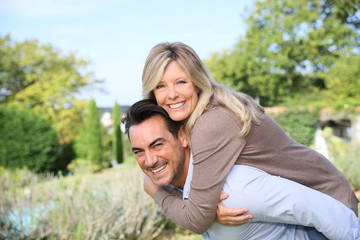 Fototapeta premium Cheerful mature man giving piggyback ride to woman