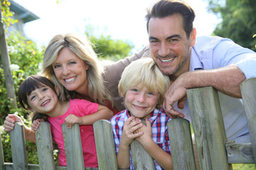 Happy family leaning on fence by country home
