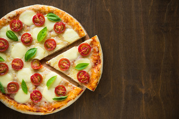 Fototapety  Pizza Margherita na ciemnym drewnianym tle widok z góry