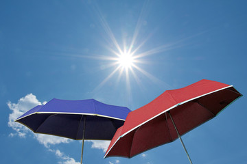 Zwei Schirme vor blauem Himmel mit strahlendem Sonnenschein