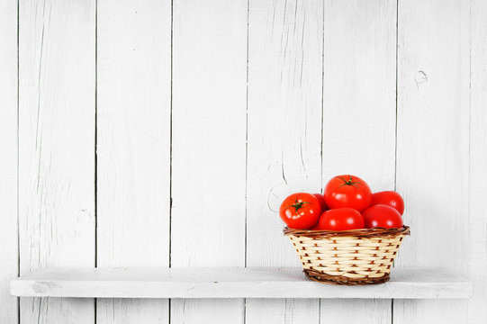 Tomatoes in a basket on wooden shelf.
