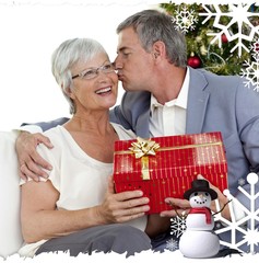 Senior man giving a kiss and a christmas present to his wife