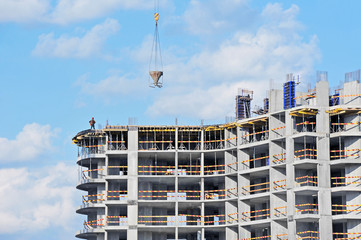 Crane lifting concrete mixer container against blue sky