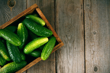 Cucumbers in a box on wooden background.