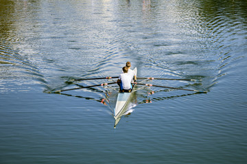 Two rowers in a boat, rowing on the tranquil lake 