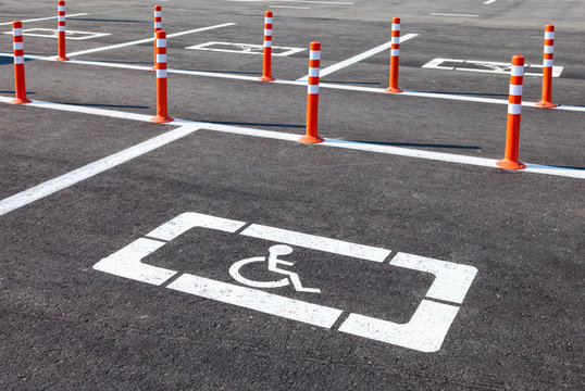 White wheelchair icon on a gray asphalt parking lot