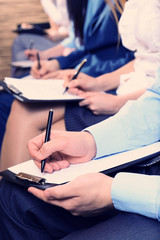 Hands holding pens and making notes at conference
