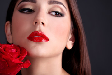 Fototapeta na wymiar Girl with red lips and rose on dark background