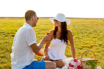 smiling couple with small red gift box on picnic
