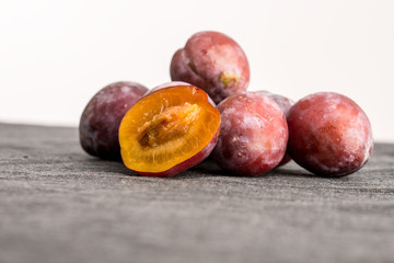 Heap of fresh plums with one halved