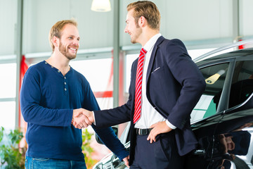 Verkäufer und Kunde mit Neuwagen von Autohaus