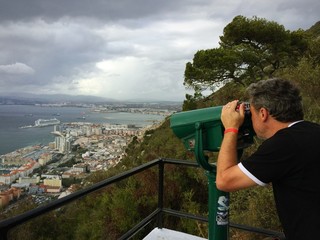 Mann blickt mit Fernrohr auf Hafen von Gibraltar
