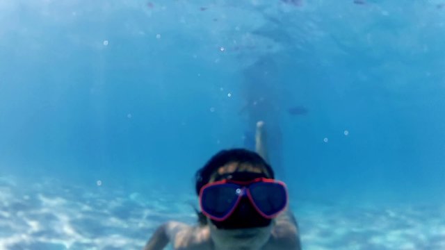 Underwater view of girl with goggles waving
