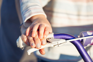 Child with parent learning riding bike - hands closeup.