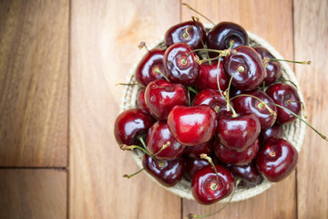 Fresh cherries in bowl on wood table