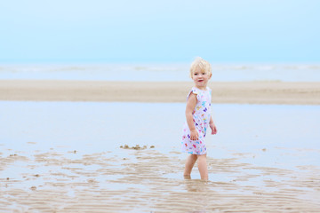 Laughing little girl plays on the beach